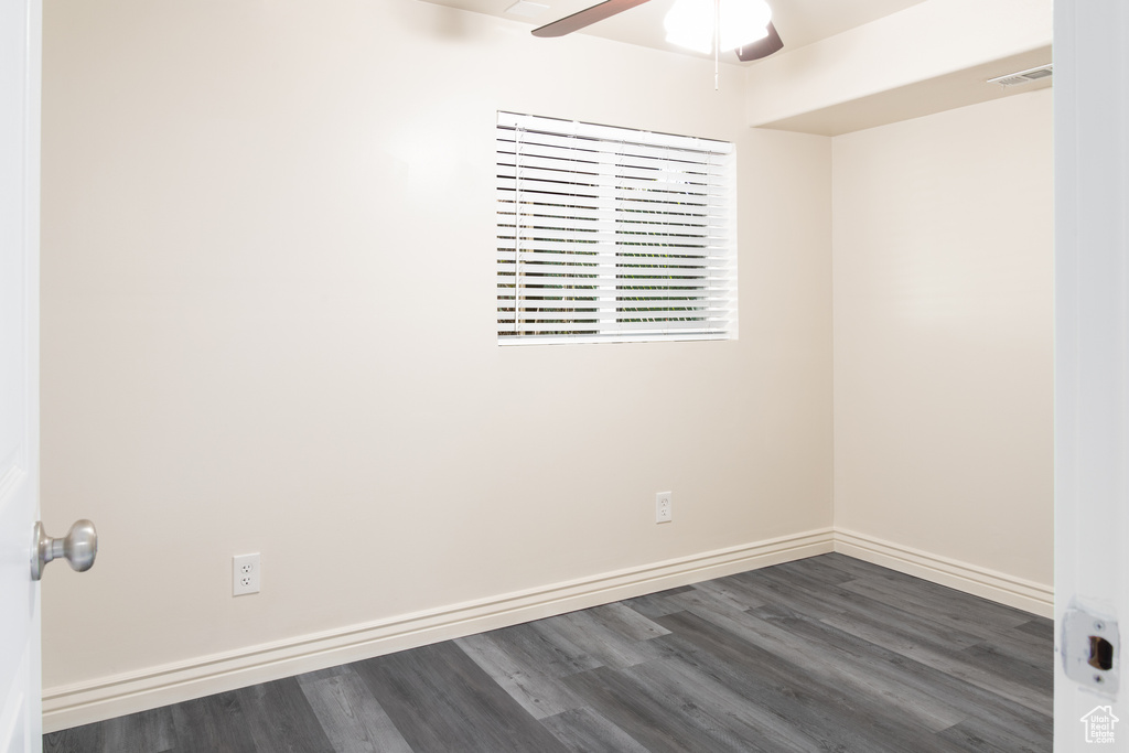 Unfurnished room with baseboards, ceiling fan, dark wood-style flooring, and visible vents