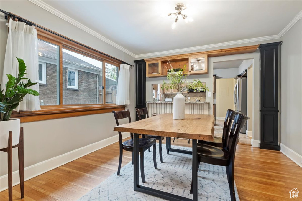 Dining space with baseboards, light wood finished floors, and crown molding