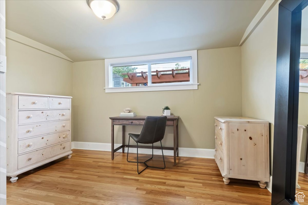 Home office with light wood-style floors, baseboards, and lofted ceiling