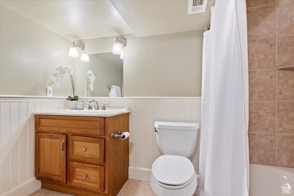 Bathroom with visible vents, vanity, toilet, tile patterned floors, and a wainscoted wall