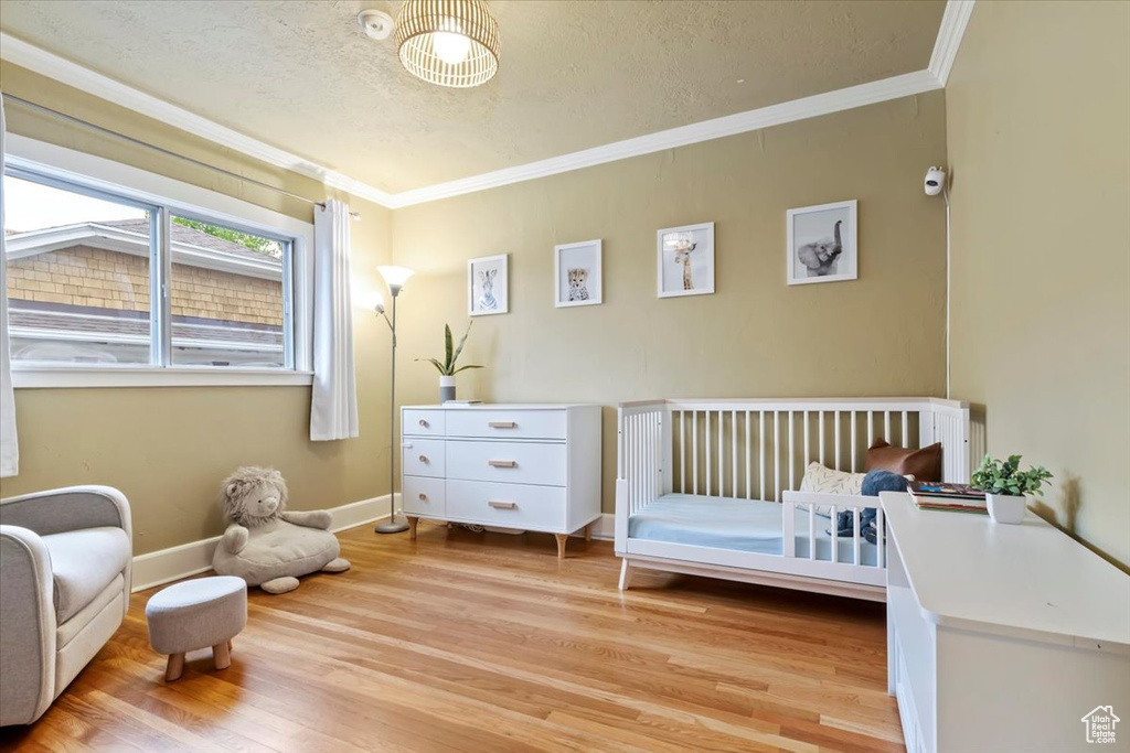 Bedroom featuring crown molding, a textured ceiling, baseboards, and light wood-style floors
