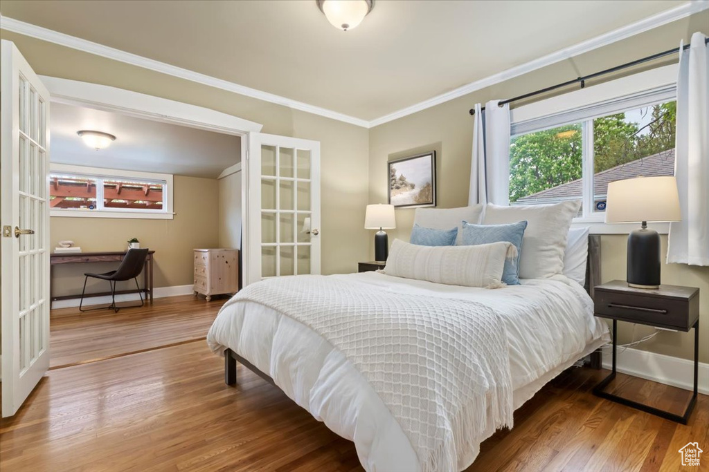 Bedroom featuring crown molding, baseboards, french doors, and wood finished floors