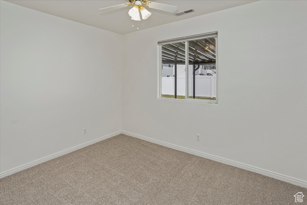 Spare room with baseboards, a ceiling fan, light colored carpet, and visible vents
