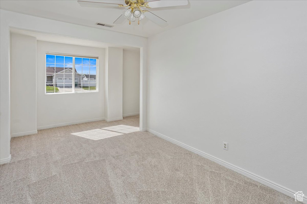 Carpeted empty room featuring a ceiling fan, baseboards, and visible vents