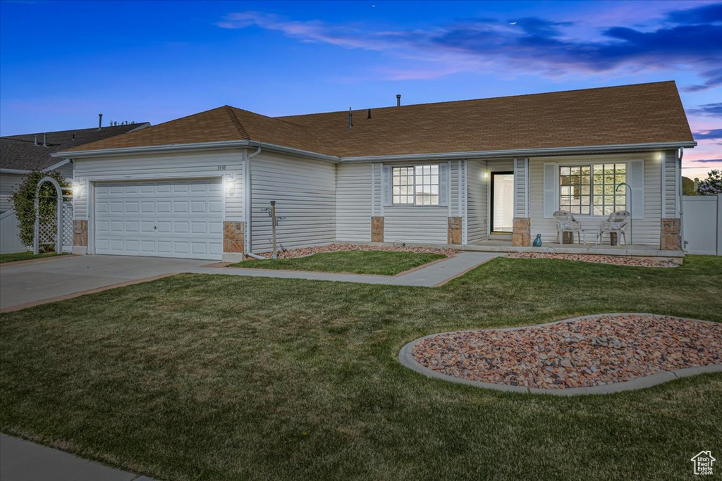 Single story home featuring a front lawn, a shingled roof, an attached garage, driveway, and a porch