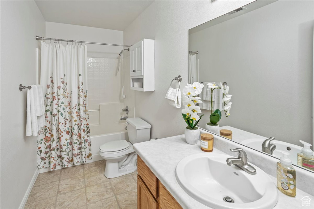 Full bathroom with vanity, toilet, baseboards, shower / tub combo, and visible vents