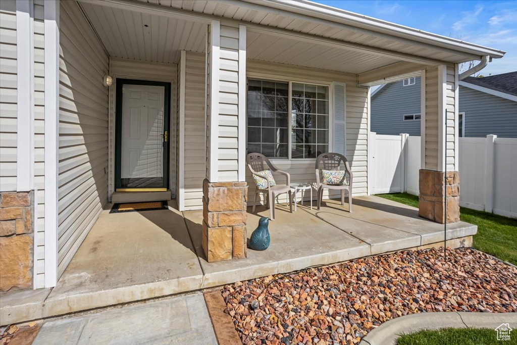 View of exterior entry with a porch and fence