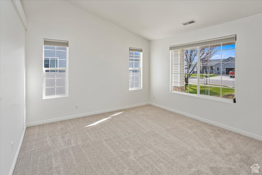 Unfurnished room featuring carpet floors, baseboards, visible vents, and lofted ceiling