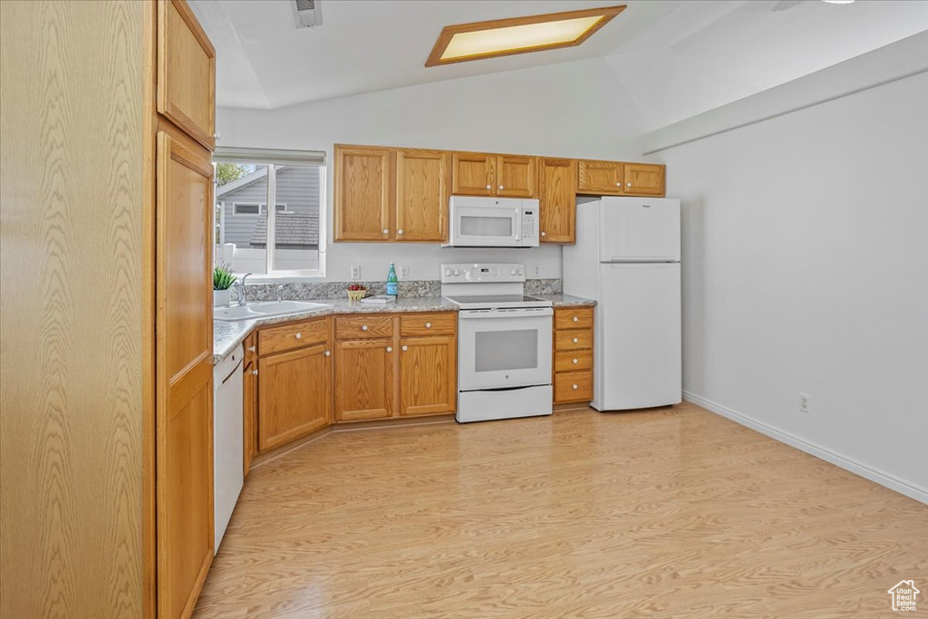 Kitchen with white appliances, baseboards, a sink, light wood finished floors, and vaulted ceiling