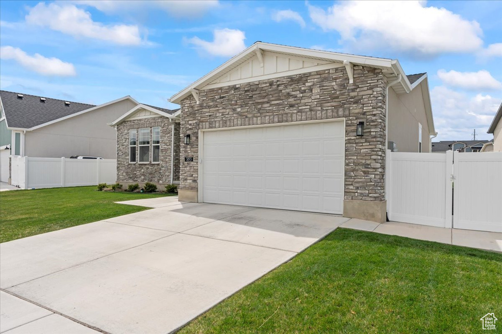 Ranch-style house featuring driveway, a garage, a front yard, and stone siding