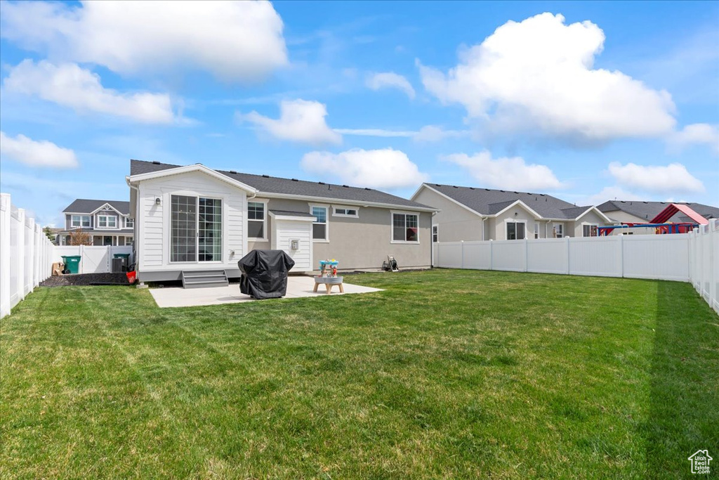 Rear view of house with a patio, a yard, and a fenced backyard