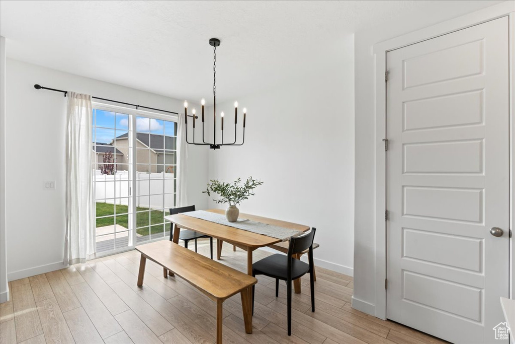 Dining space with baseboards, light wood-type flooring, and an inviting chandelier