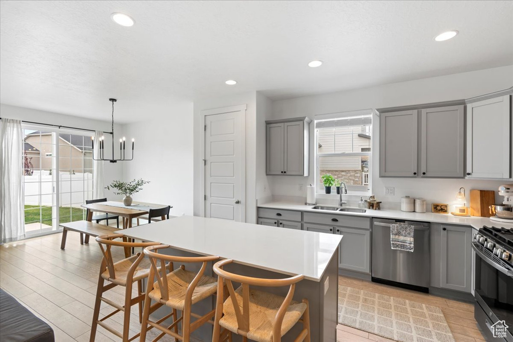 Kitchen with gray cabinetry, a sink, stainless steel appliances, and plenty of natural light