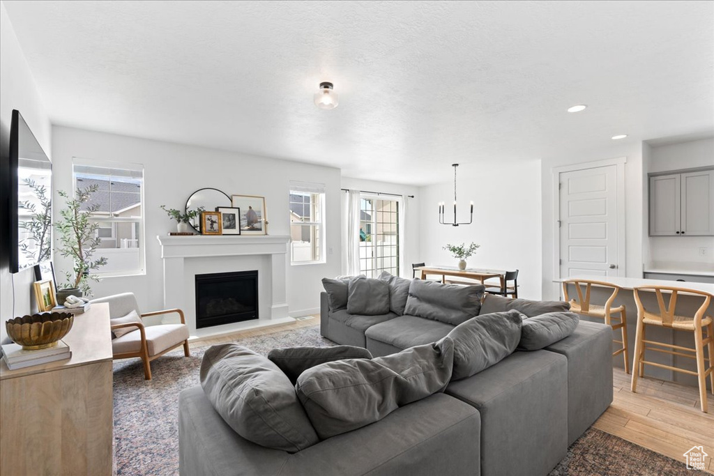 Living area featuring light wood-type flooring, recessed lighting, a fireplace with raised hearth, and plenty of natural light