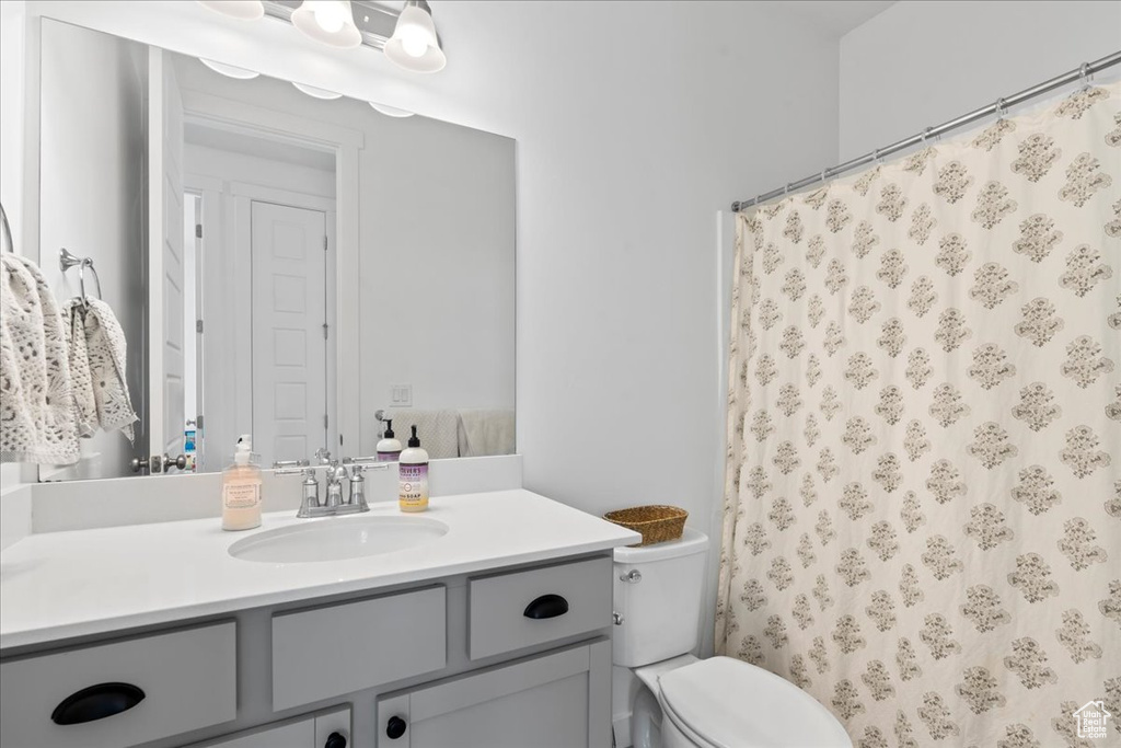 Bathroom featuring a shower with shower curtain, toilet, and vanity