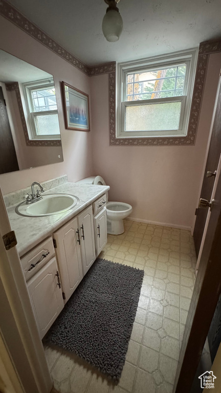 Bathroom with toilet, tile patterned floors, baseboards, and vanity