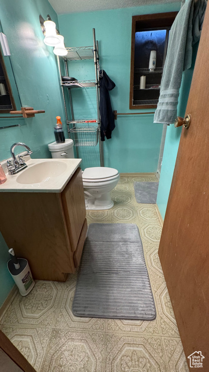Bathroom with toilet, a textured ceiling, and vanity