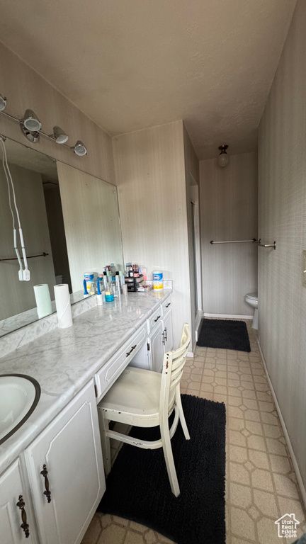 Bathroom with vanity, toilet, tile patterned floors, baseboards, and a stall shower