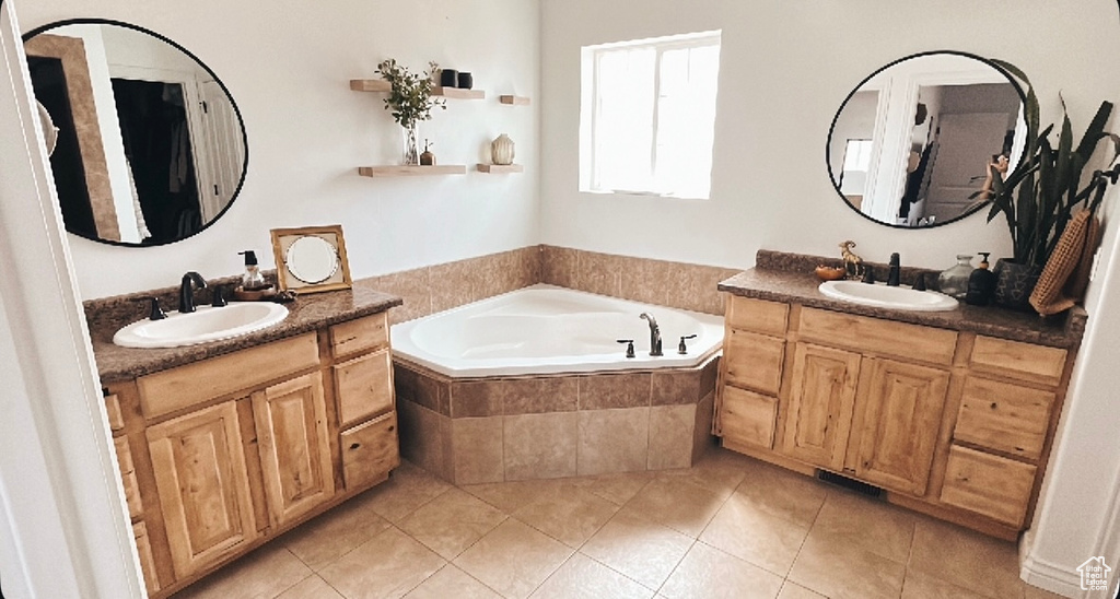 Bathroom featuring tile patterned flooring, two vanities, a sink, and a garden tub