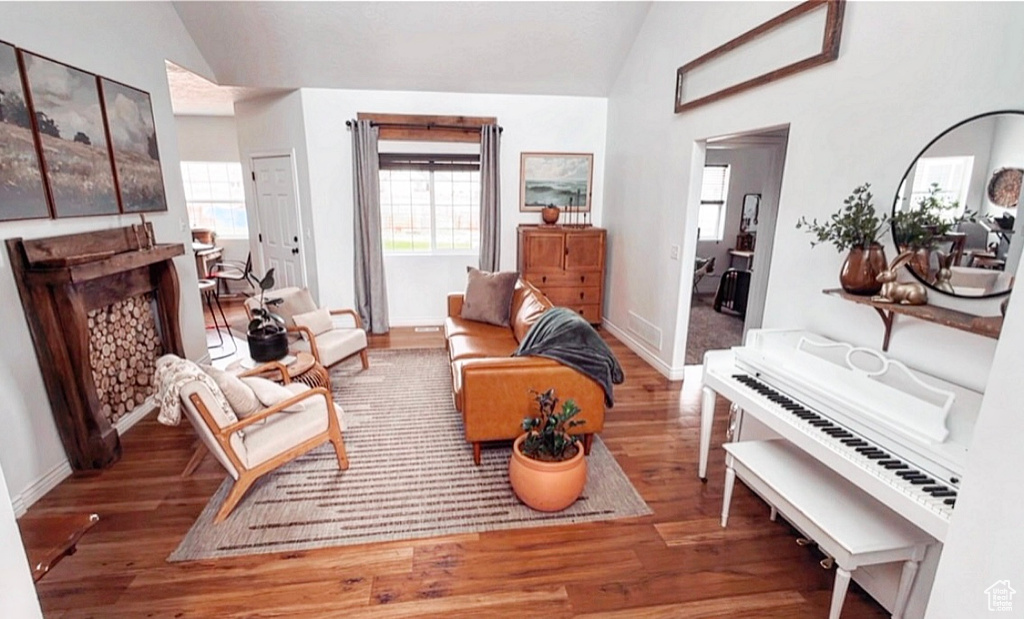 Living room with baseboards, wood finished floors, vaulted ceiling, and a fireplace