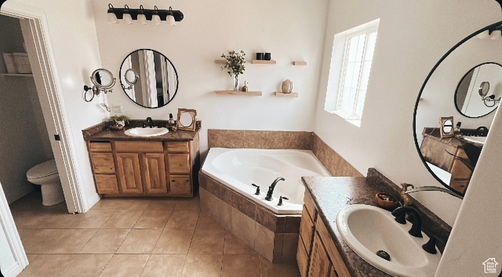 Bathroom featuring a sink, a bath, tile patterned floors, and two vanities