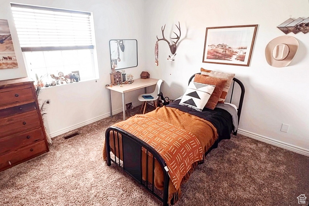 Carpeted bedroom featuring baseboards and visible vents