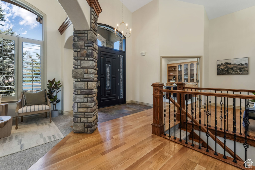 Entrance foyer featuring baseboards, decorative columns, a towering ceiling, and a notable chandelier