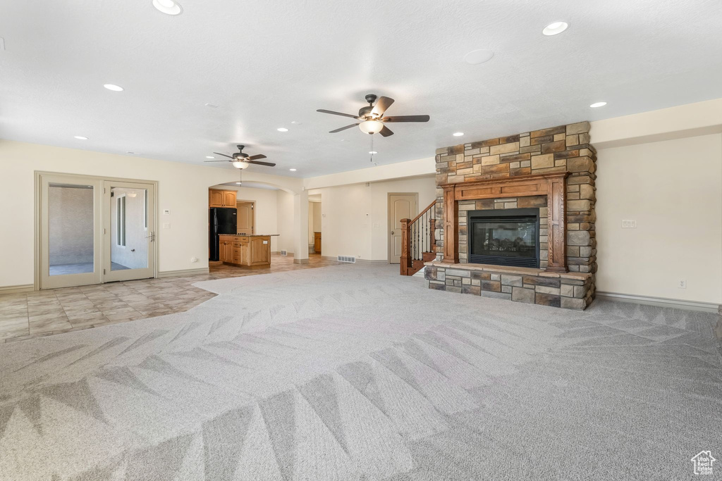 Unfurnished living room with light colored carpet, arched walkways, ceiling fan, and recessed lighting