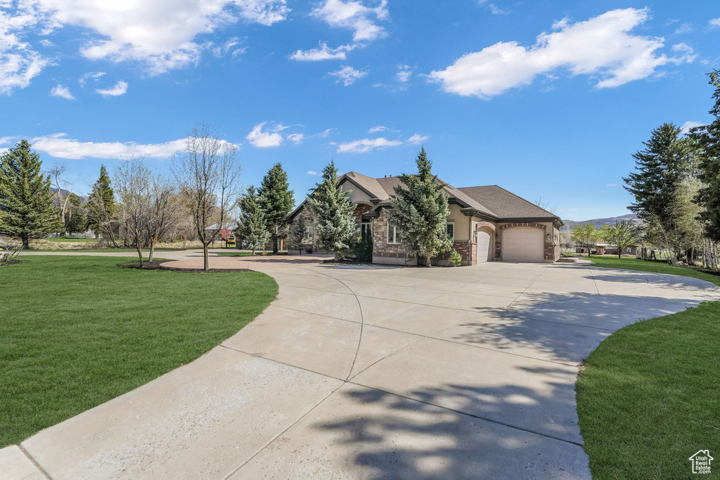 View of front facade featuring brick siding, driveway, a front lawn, and a garage