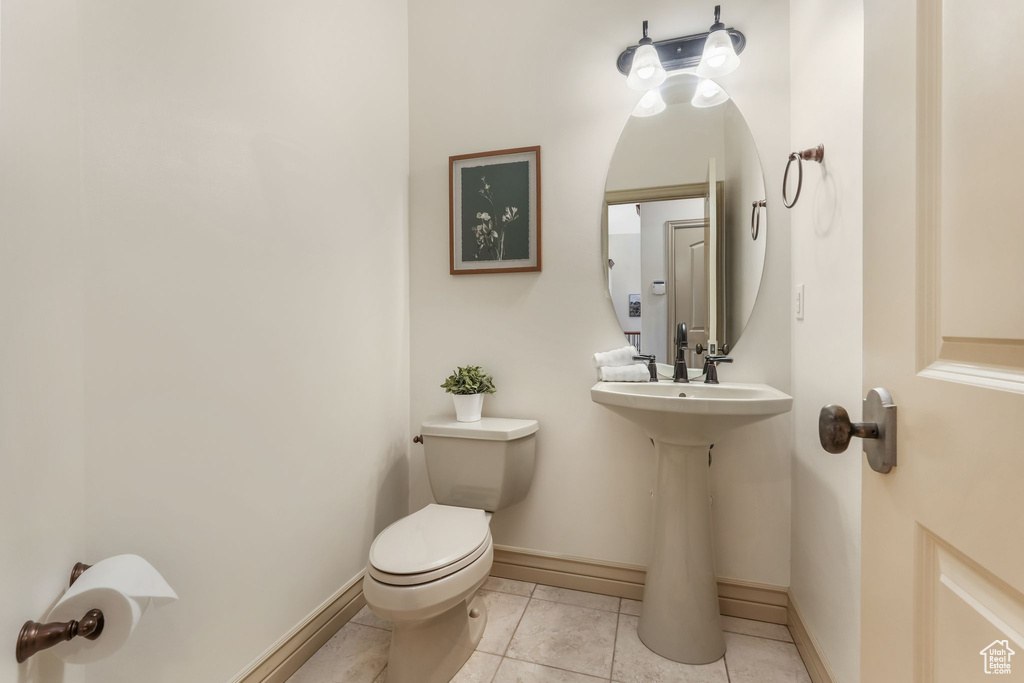 Half bath featuring toilet, baseboards, and tile patterned flooring