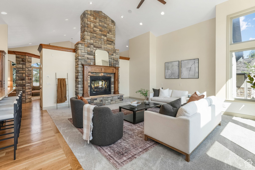 Living room featuring decorative columns, wood finished floors, a fireplace, ceiling fan, and high vaulted ceiling