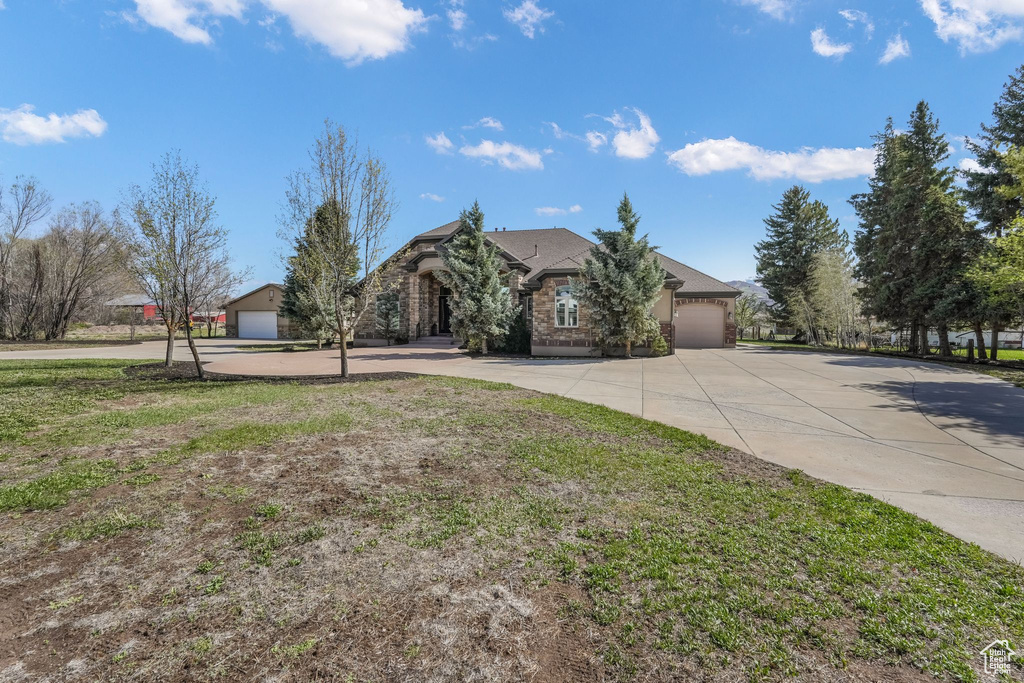 View of front of home with an attached garage, driveway, and a front yard
