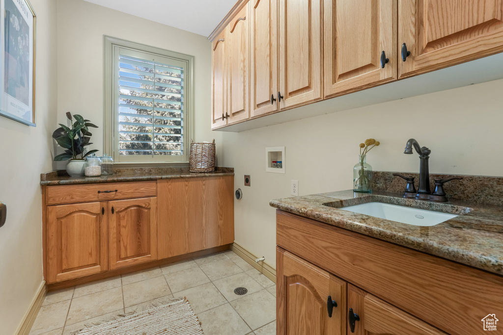 Washroom featuring baseboards, hookup for a washing machine, electric dryer hookup, a sink, and cabinet space