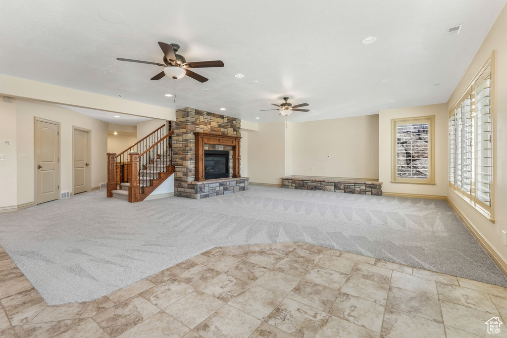 Unfurnished living room with ceiling fan, a stone fireplace, baseboards, carpet flooring, and recessed lighting