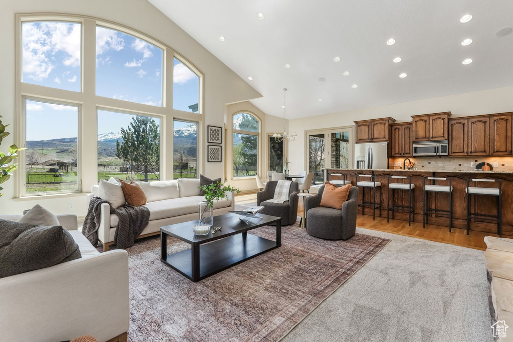 Living area with recessed lighting, a mountain view, high vaulted ceiling, and light wood-type flooring