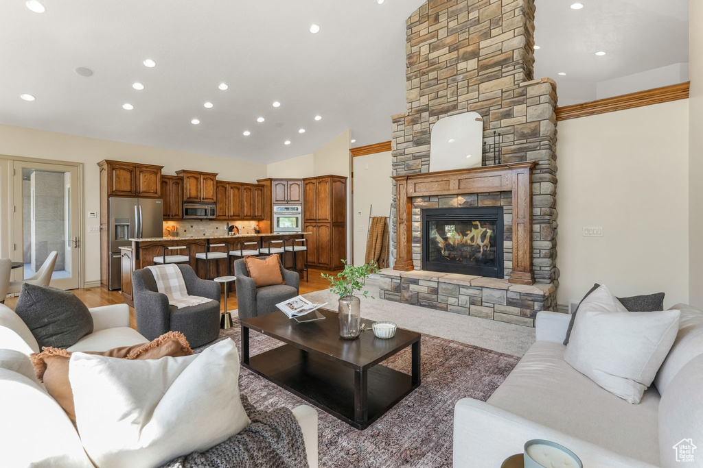 Living room with recessed lighting, high vaulted ceiling, and a stone fireplace