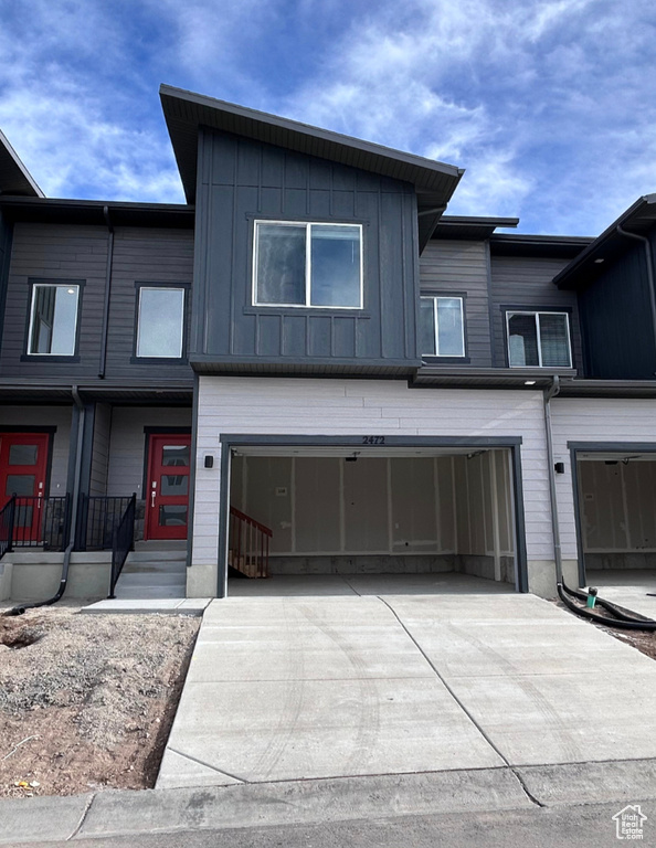 View of property with concrete driveway, board and batten siding, and a garage