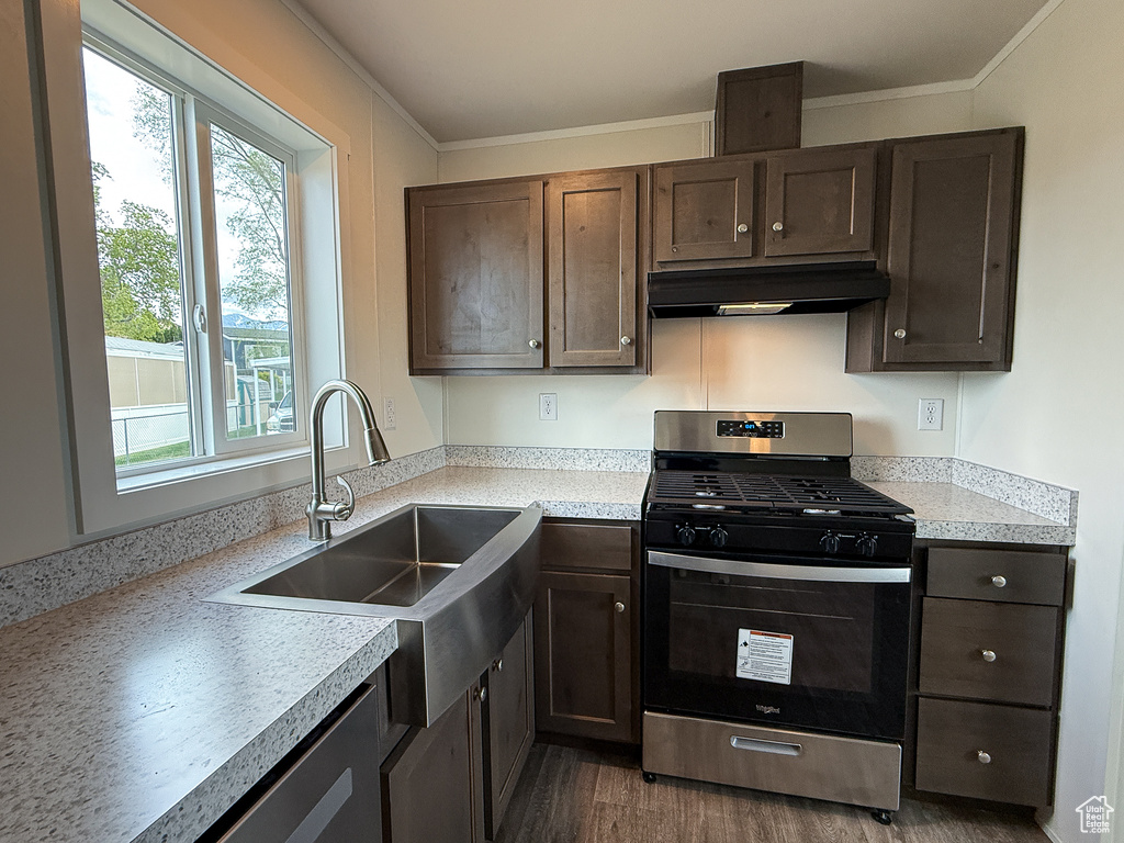 Kitchen with a sink, stainless steel range with gas stovetop, under cabinet range hood, and plenty of natural light
