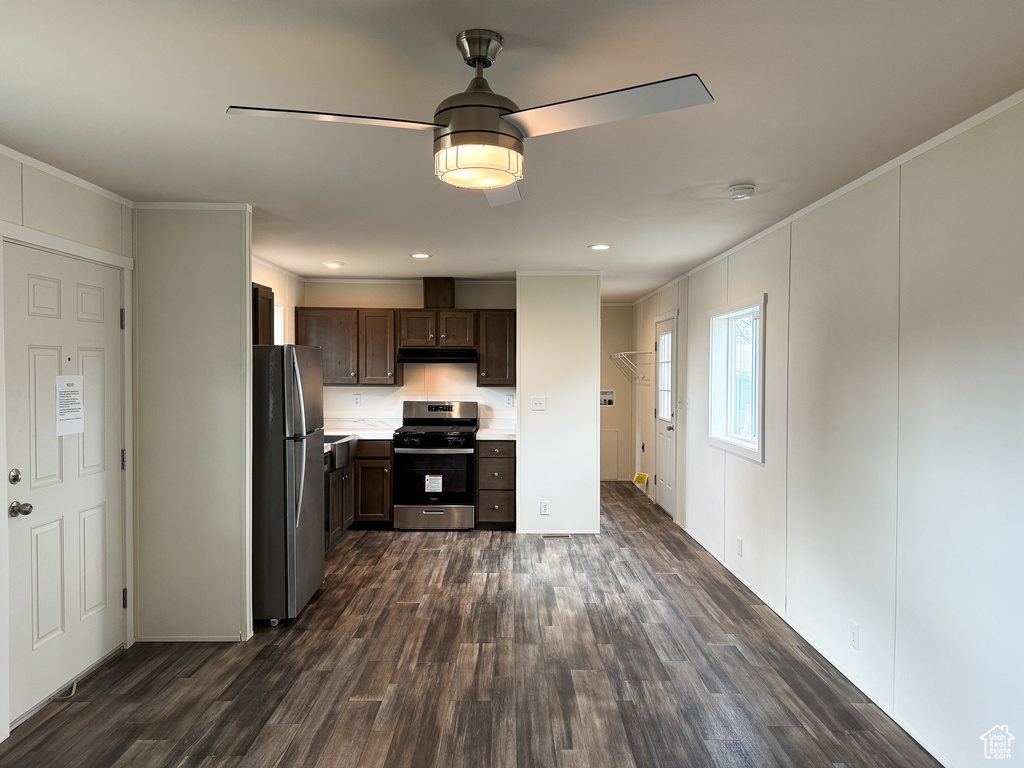 Kitchen with dark wood finished floors, dark brown cabinetry, under cabinet range hood, appliances with stainless steel finishes, and light countertops
