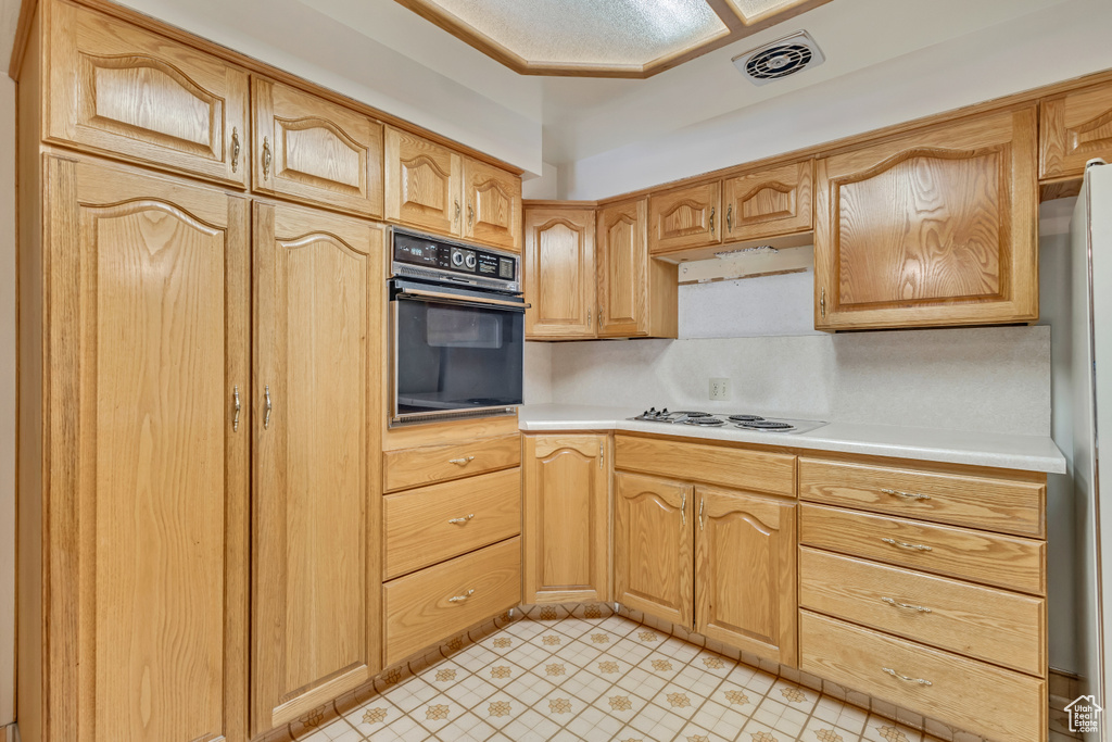Kitchen featuring light countertops, black oven, visible vents, and white electric cooktop