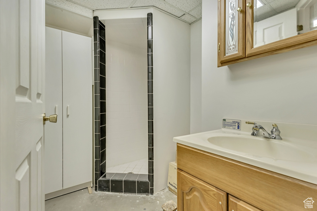 Full bath featuring vanity, a stall shower, concrete floors, and a drop ceiling