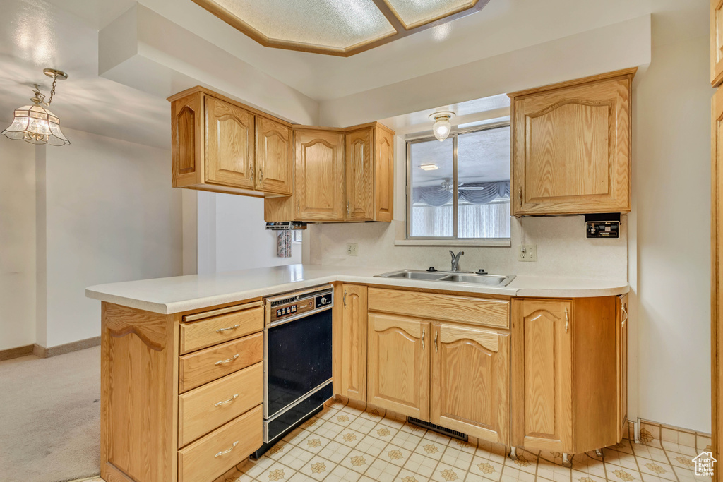 Kitchen featuring a peninsula, light brown cabinets, baseboards, light countertops, and a sink