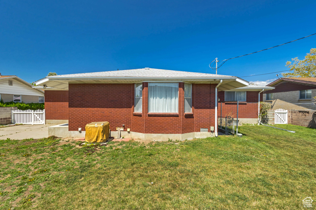 View of home's exterior featuring fence, a yard, and brick siding