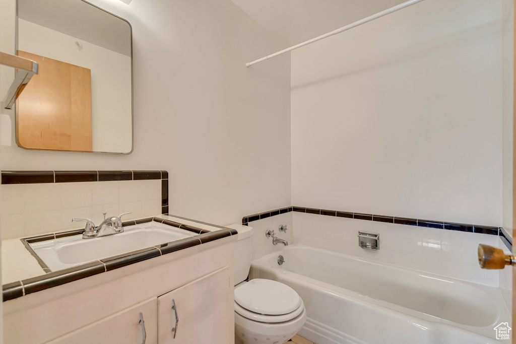 Bathroom with vanity, a bathtub, toilet, and tasteful backsplash
