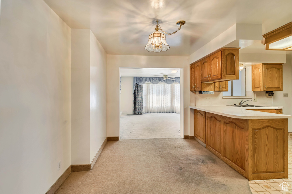 Kitchen with light colored carpet, light countertops, baseboards, a sink, and an inviting chandelier