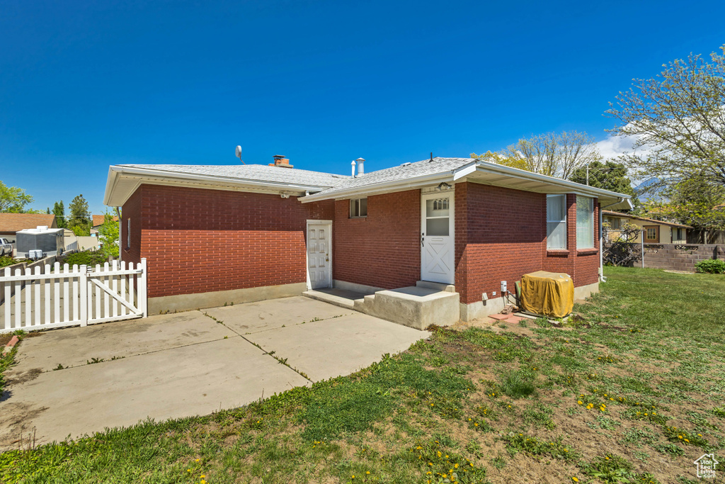 Back of property with fence, a patio, a lawn, and brick siding