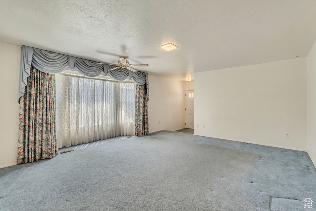 Unfurnished living room with carpet flooring and a ceiling fan