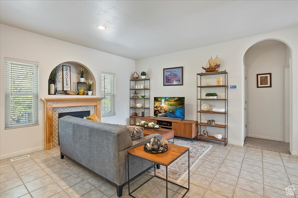 Living room with visible vents, arched walkways, a fireplace, and plenty of natural light