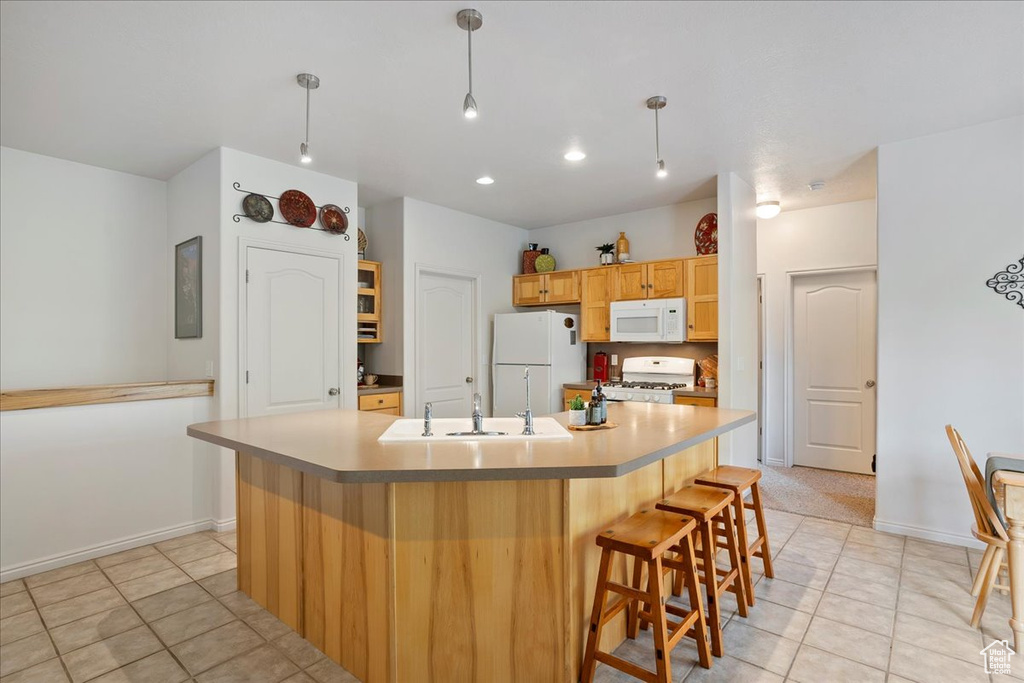 Kitchen with a kitchen breakfast bar, a sink, baseboards, light tile patterned flooring, and white appliances