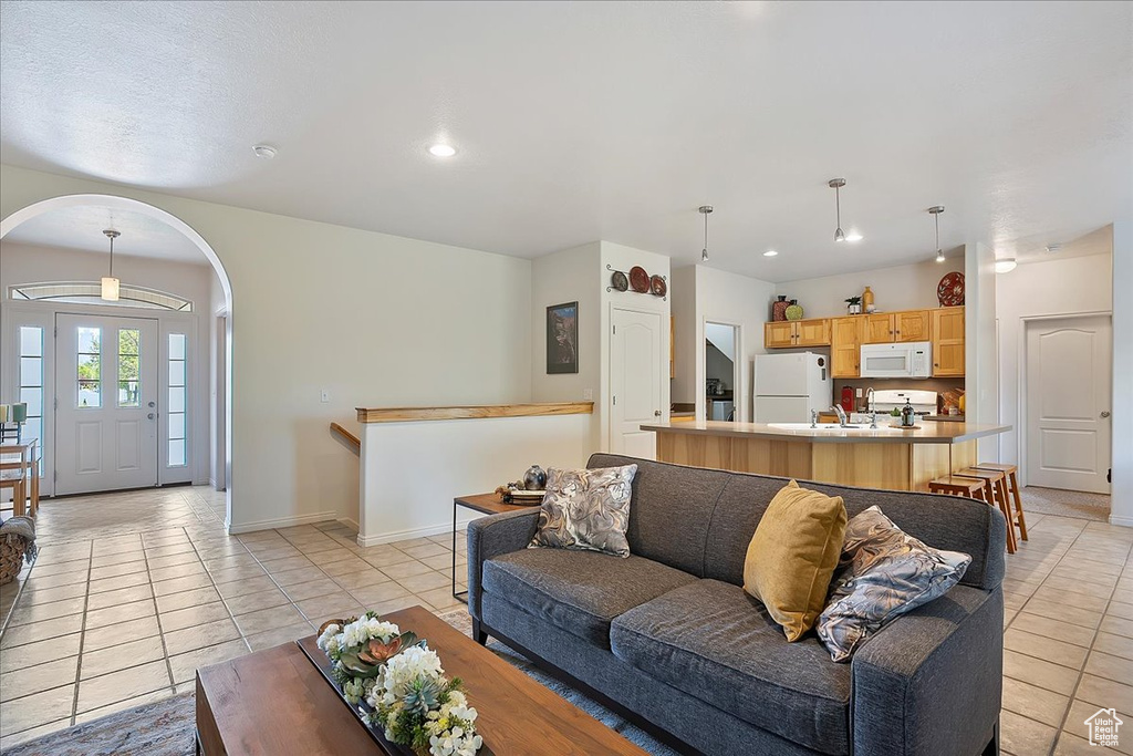 Living room with baseboards, recessed lighting, light tile patterned floors, and arched walkways